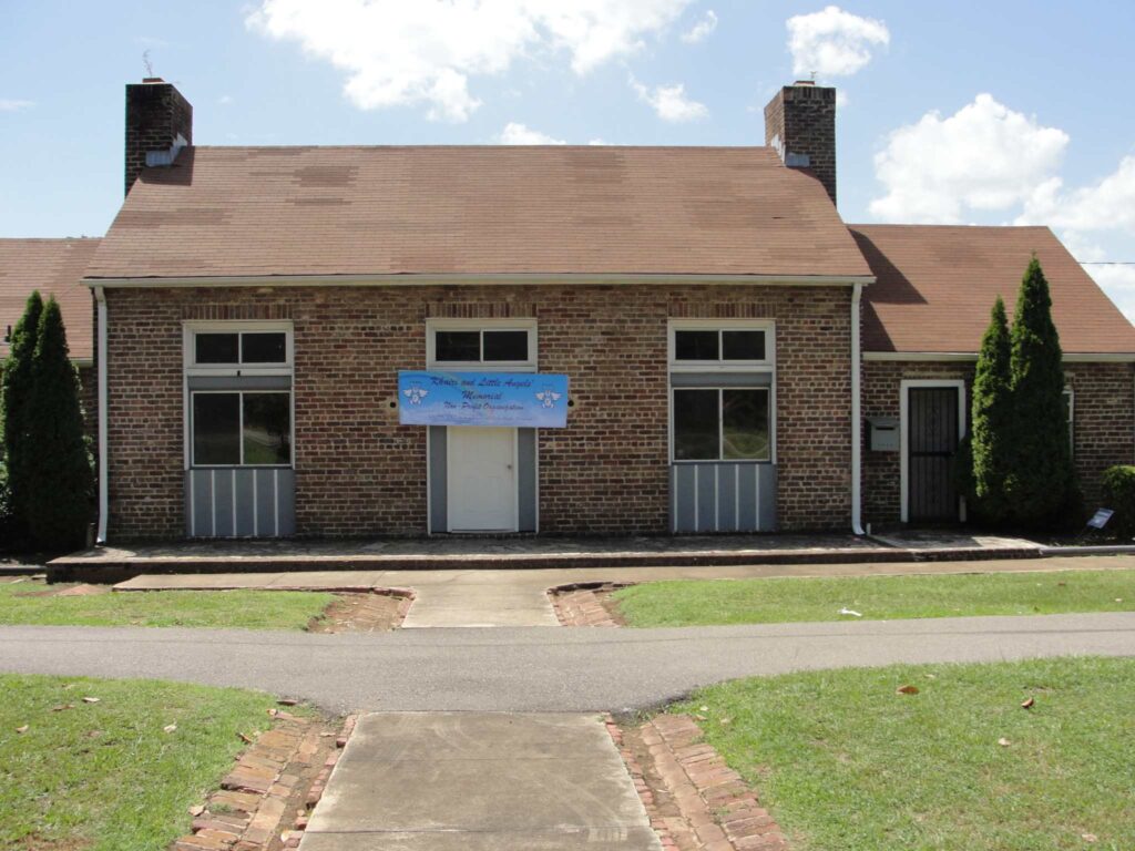 a large brick building with grass in front of a house