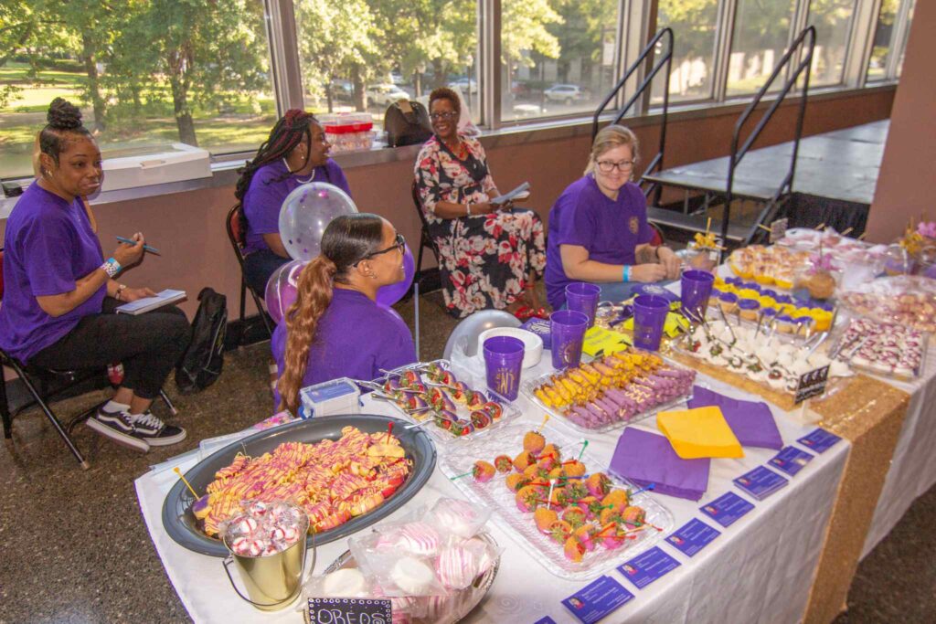 a group of people sitting at a table with a cake