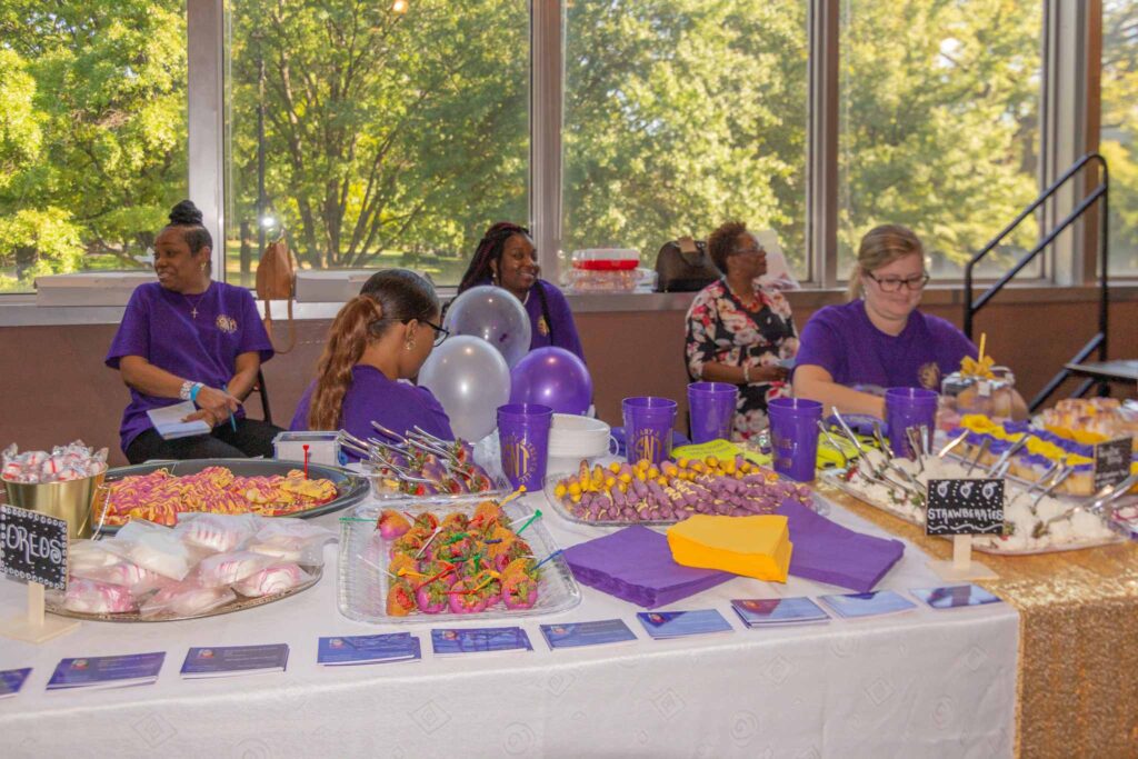 a group of people sitting at a table with a birthday cake